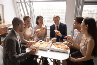 Mutlu çeşitli çalışanlar, birlikte pizza yiyip eğleniyorlar.