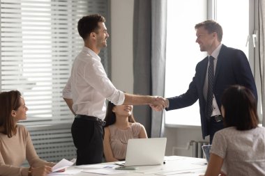 Toplantıda gülümseyen işadamı lideri çalışanın elini sıkıyor
