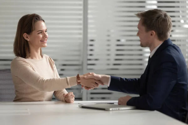 Впевнений бізнесмен потискає руку усміхненої бізнес-леді в офісі — стокове фото