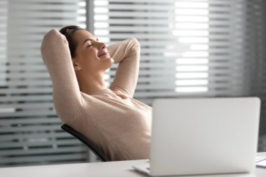 Mola sırasında rahat ofis koltuğunda dinlenen tatmin olmuş iş kadını.