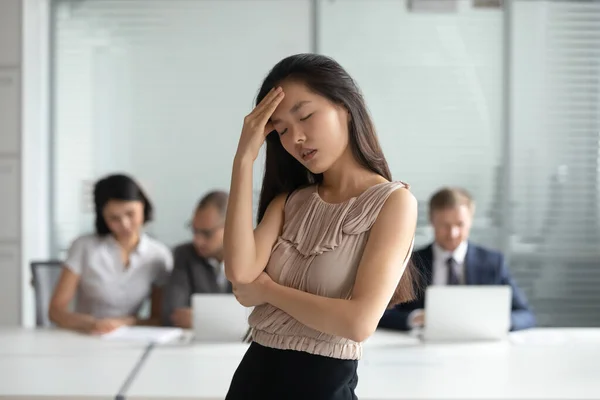 Unhappy Asian businesswoman suffering from headache, touching forehead — Stockfoto