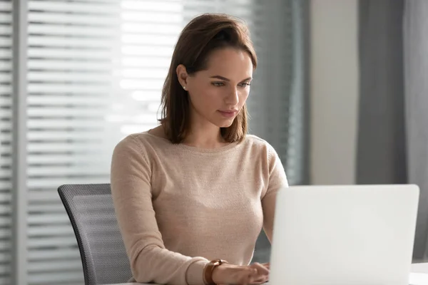 Serieuze zakenvrouw die laptop gebruikt, naar het scherm kijkt, aan het project werkt — Stockfoto