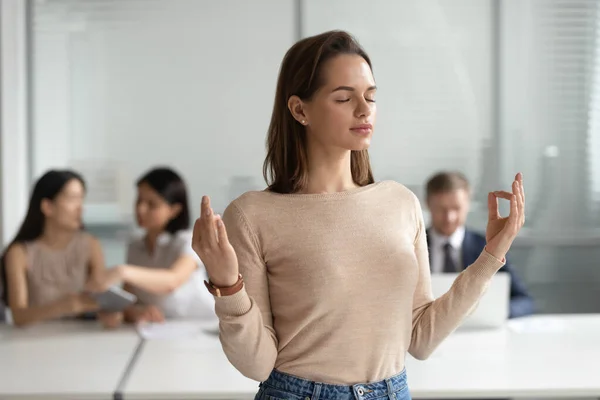 Mindful young businesswoman meditating, doing yoga exercise in office — Stock Photo, Image
