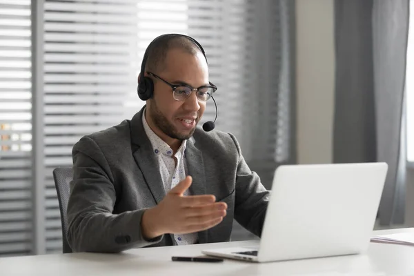 Smiling African American employee in headset using laptop, talking online — Stock Photo, Image