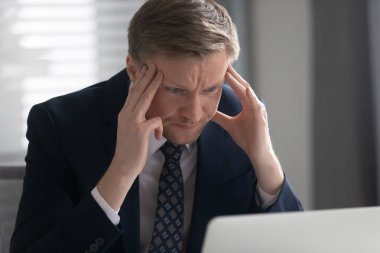 Stresli iş adamı tapınaklara dokunuyor, zor projeler üzerinde kafa yoruyor.