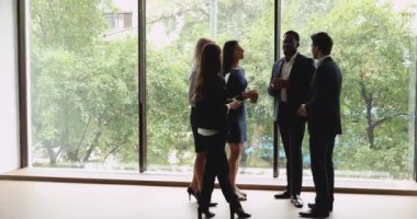 Çok ırklı erkek ve kadın profesyonel meslekdaşlar ofiste konuşuyorlar.