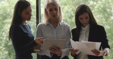 Ciddi yaşlı kadın akıl hocası yönetici ofiste genç stajyerleri bilgilendiriyor.