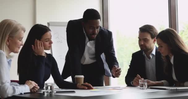 Mentor de gerente masculino africano focado e equipe multiétnica analisam papelada — Vídeo de Stock