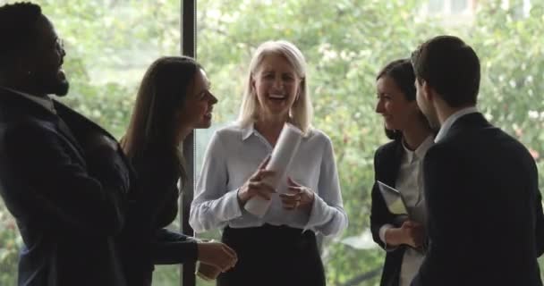 Cheerful old and young multiracial colleagues laughing standing in office — Stock video