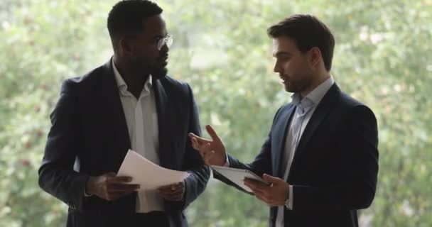 Focused african and caucasian partners discussing project holding papers tablet — Stock Video