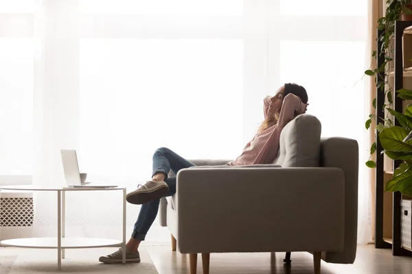 Relaxado jovem mulher descansando no sofá confortável na sala de estar — Fotografia de Stock