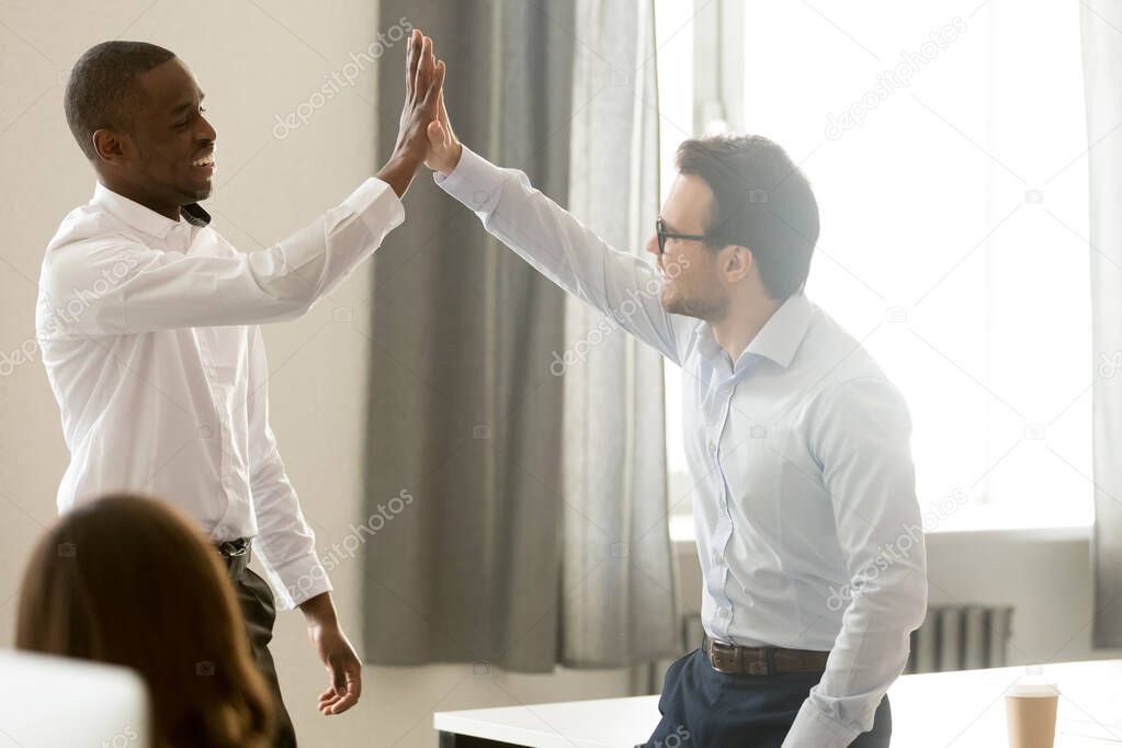 African and caucasian businessmen corporate employees giving high five