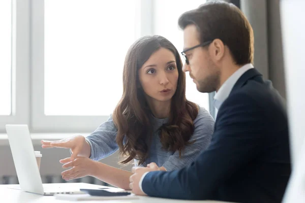 Employés sérieux de femme et d'homme utilisant des statistiques en ligne discutant des résultats — Photo