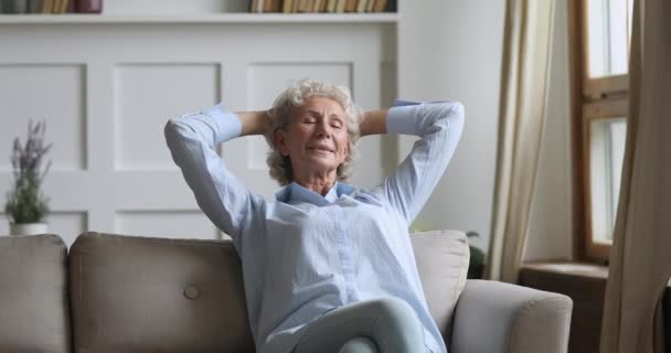 Feliz anciana sana relajándose con los ojos cerrados en el sofá — Vídeos de Stock