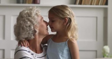 Mutlu yaşlı büyükanne kucaklıyor küçük torunu evde gülüyor.
