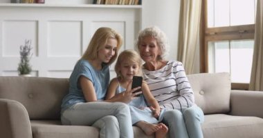 Mutlu üç nesil aile babaannesi ve torunu telefon kullanıyor.
