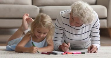 Yaşlı büyükanne küçük torununa keçeli kalemle çizim yapmayı öğretiyor.