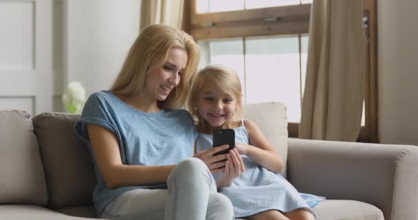 Roztomilý šťastný dítě dívka baví s maminkou pomocí telefonu — Stock video