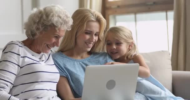 Счастливая семья из трех поколений с помощью ноутбука смотрит смешные мультфильмы — стоковое видео