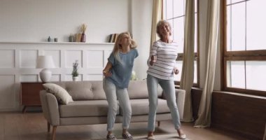 Aktif iki nesil kadınlar oturma odasında dans ediyor.
