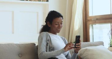 Mutlu Afrikalı genç bayan evde akıllı telefon kullanmaktan zevk alıyor.