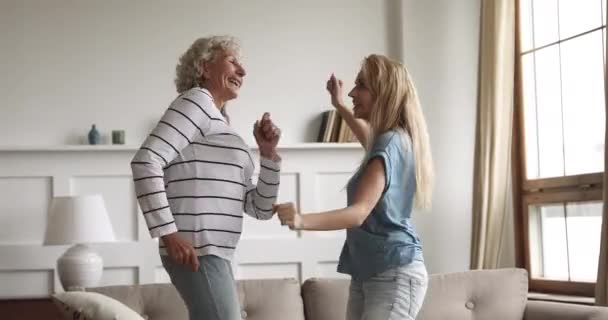 Счастливая беззаботная молодая дочь и старая мать танцуют дома — стоковое видео
