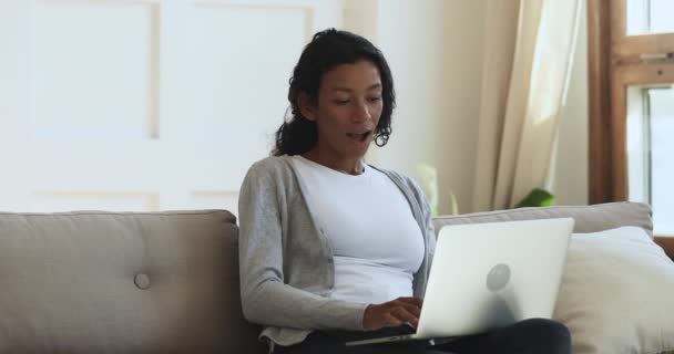 Захоплений переможець африканської жінки за допомогою ноутбука святкує перемогу в онлайн-програмі — стокове відео