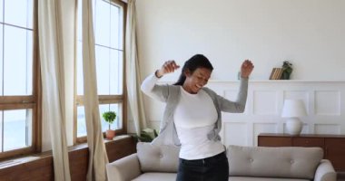 Kaygısız neşeli Afrikalı kadın evde tek başına dans ederek zıplıyor.