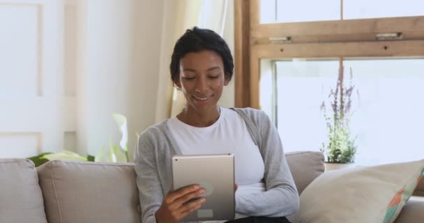 Sorprendido alegre joven africana ganar en la tableta en casa — Vídeo de stock