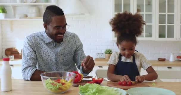 Szczęśliwy afrykański tata uczyć małą córkę wyciąć zdrową sałatkę razem — Wideo stockowe