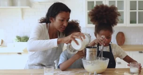 Jeune maman africaine femme au foyer préparant la pâte avec petite fille fils — Video