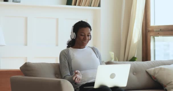 Happy african woman wear headphones making video call on laptop — Stock Video