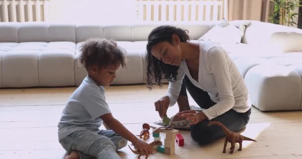 Африканська мама з малим сином грають іграшки сидять на підлозі. — стокове відео