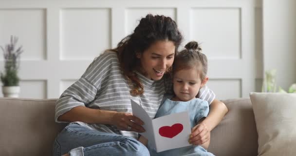 Feliz mamá y niña pequeña hija sosteniendo la lectura de la tarjeta de felicitación — Vídeos de Stock