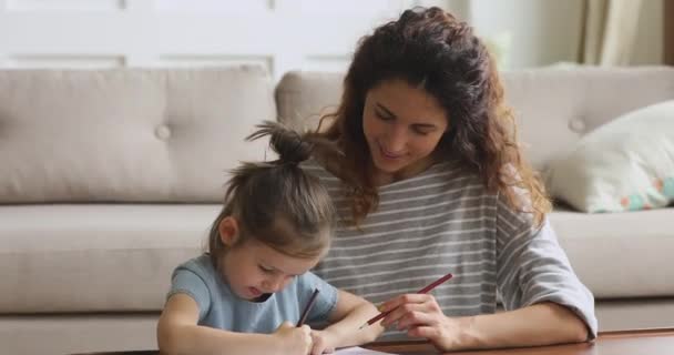 Leende mor hjälpa barn dotter rita med pennor hemma — Stockvideo