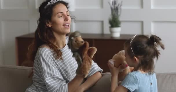Игривая мама в короне играет в кукольные игрушки с маленькой дочкой — стоковое видео