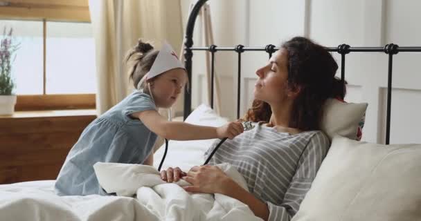 Słodkie dziewczyna grać jako lekarz pielęgniarka słuchając mama z stetoskop — Wideo stockowe