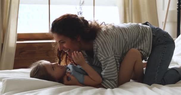 Zorgeloze moeder en kind dochter hebben plezier spelen op bed — Stockvideo