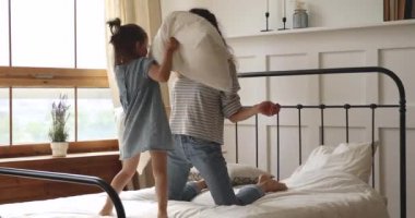 Mutlu anne ve çocuk yatakta yastık savaşı yapıyor.