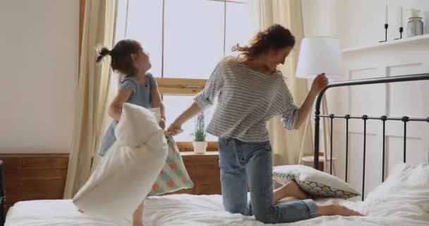 Boldog anya és óvodás gyerek élvezik párnacsata az ágyban — Stock videók