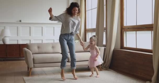 Carefree joyful mom and kid daughter jumping dancing at home — Stock Video