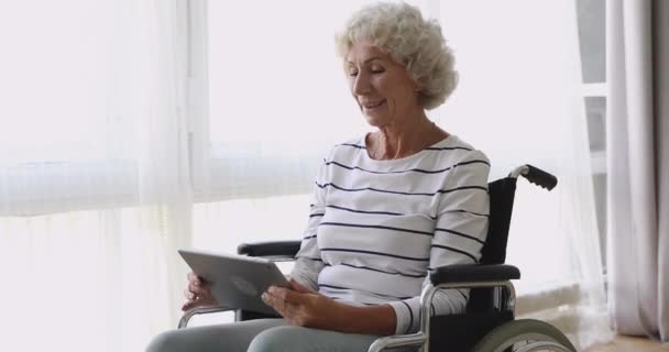 Mujer mayor feliz sentarse en silla de ruedas usando tableta digital — Vídeo de stock