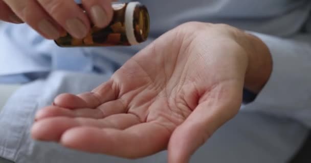 Старшая женщина наливает таблетки на руку, принимая лекарства, закрыть — стоковое видео