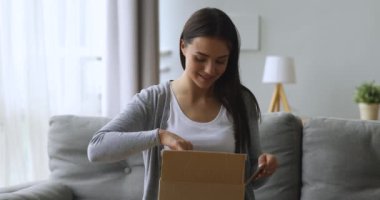 Memnun bayan müşteri. Paket kutusunu açın. Kanepeye oturun.