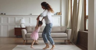 Aktif anne, dönen kızı kaldırıyor oturma odasında dans ediyor.