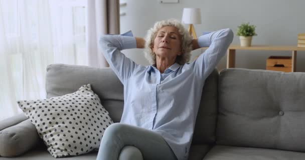 Tranquilo anciana serena descansando en el sofá con los ojos cerrados — Vídeos de Stock