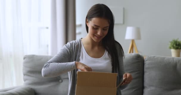 Caja de paquete abierta de cliente femenino satisfecho sentarse en el sofá — Vídeo de stock