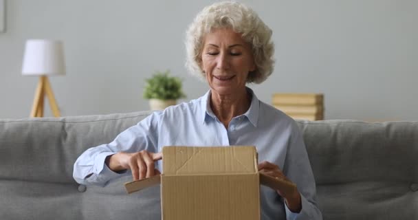 Felice vecchia donna anziana pacchetto aperto in soggiorno — Video Stock