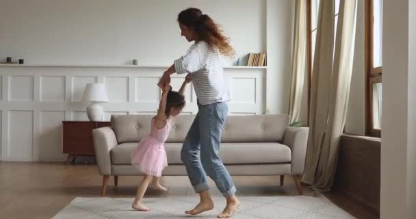 Активная мама поднимает крутящегося ребенка дочь танцует в гостиной — стоковое видео