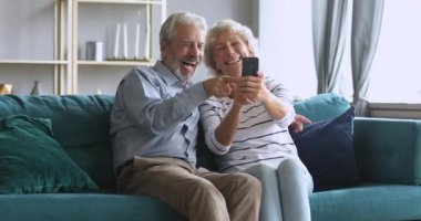 Mutlu yaşlı çift evde akıllı telefondan selfie çekiyor.